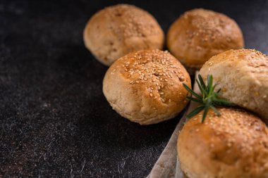 Kırsal arka planda susam tohumlu ev yapımı kahverengi çörekler. Sağlıklı zanaatkar ekmeği.