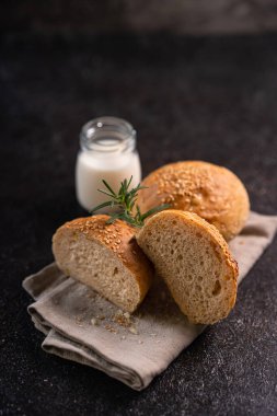 Kırsal arka planda susam tohumlu ev yapımı kahverengi çörekler. Sağlıklı zanaatkar ekmeği.