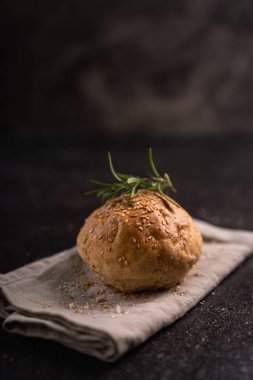 Kırsal arka planda susam tohumlu ev yapımı kahverengi çörekler. Sağlıklı zanaatkar ekmeği.