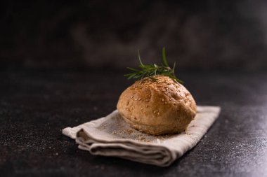 Kırsal arka planda susam tohumlu ev yapımı kahverengi çörekler. Sağlıklı zanaatkar ekmeği.