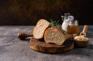 Taze ev yapımı ekmek ekmeği baget ekmeği beyaz süt ve kır tahtası ve soyut masa üzerinde bal. Ekmek