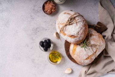 Taze organik ciabatta ekmeği, otlar, zeytinyağı ve beyaz kırsal arka planda zeytinyağı. mayalı ekmek