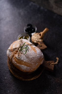 Siyah kırsal bir masada zeytin ve biberiyeli taze pişmiş ekşi ekşi ciabatta ekmeği. Esnaf ekmeği