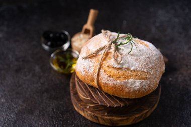 Siyah kırsal bir masada zeytin ve biberiyeli taze pişmiş ekşi ekşi ciabatta ekmeği. Esnaf ekmeği