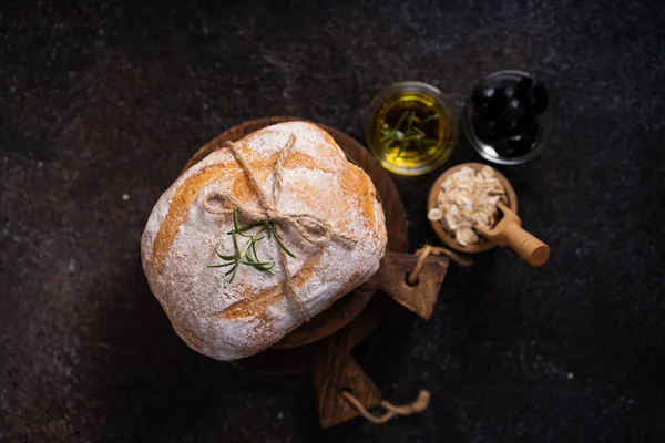 黒いロマンチックなテーブルの上にオリーブとローズマリーを添えた焼きそばのパン アーティサンパン — ストック写真