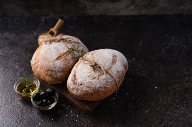 Siyah kırsal bir masada zeytin ve biberiyeli taze pişmiş ekşi ekşi ciabatta ekmeği. Esnaf ekmeği