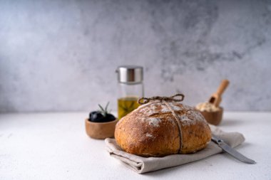 Beyaz soyut bir masa üzerinde zeytinli ve biberiyeli taze pişmiş ekşi ekşi ciabatta ekmeği. Esnaf ekmeği