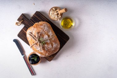 Beyaz soyut bir masa üzerinde zeytinli ve biberiyeli taze pişmiş ekşi ekşi ciabatta ekmeği. Esnaf ekmeği