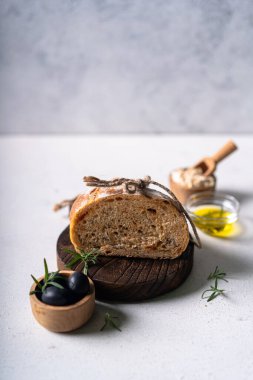 Beyaz soyut bir masa üzerinde zeytinli ve biberiyeli ev yapımı ekşi ciabatta dilimi. Esnaf ekmeği