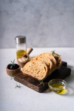 Beyaz soyut bir masa üzerinde zeytinli ve biberiyeli ev yapımı ekşi ciabatta dilimi. Esnaf ekmeği