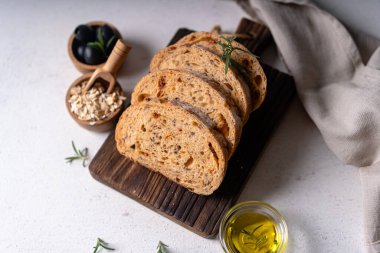 Beyaz soyut bir masa üzerinde zeytinli ve biberiyeli ev yapımı ekşi ciabatta dilimi. Esnaf ekmeği