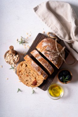 Beyaz soyut bir masa üzerinde zeytinli ve biberiyeli ev yapımı ekşi ciabatta dilimi. Esnaf ekmeği