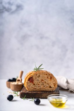 Beyaz soyut bir masa üzerinde zeytinli ve biberiyeli ev yapımı ekşi ciabatta dilimi. Esnaf ekmeği