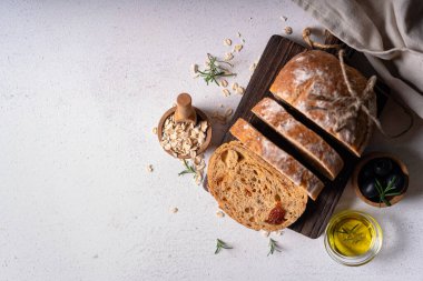Beyaz soyut bir masa üzerinde zeytinli ve biberiyeli ev yapımı ekşi ciabatta dilimi. Esnaf ekmeği