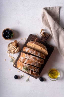 Beyaz soyut bir masa üzerinde zeytinli ve biberiyeli ev yapımı ekşi ciabatta dilimi. Esnaf ekmeği
