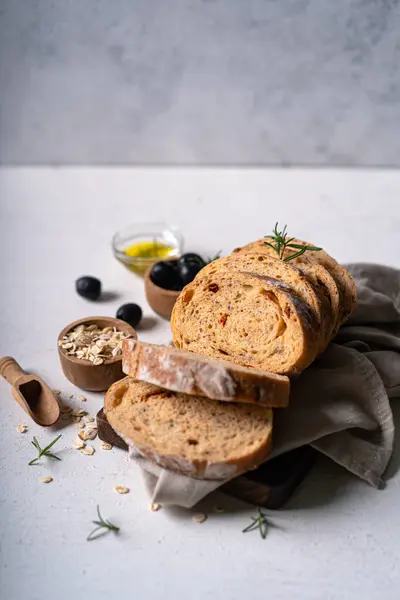 Beyaz soyut bir masa üzerinde zeytinli ve biberiyeli ev yapımı ekşi ciabatta dilimi. Esnaf ekmeği