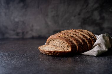 Tam tahıllı undan dilimlenmiş ekşi ekmek ve ızgarada kabak çekirdeği, kırsal bir ahşap masada zeytin yağı ve siyah zeytin. Esnaf ekmeği.