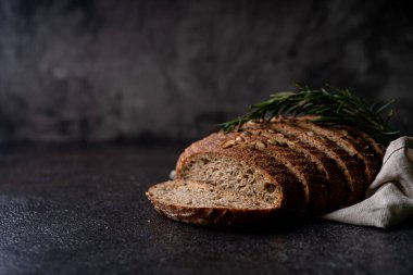 Tam tahıllı undan dilimlenmiş ekşi ekmek ve ızgarada kabak çekirdeği, kırsal bir ahşap masada zeytin yağı ve siyah zeytin. Esnaf ekmeği.