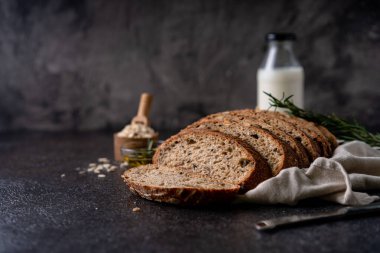 Tam tahıllı undan dilimlenmiş ekşi ekmek ve ızgarada kabak çekirdeği, kırsal bir ahşap masada zeytin yağı ve siyah zeytin. Esnaf ekmeği.