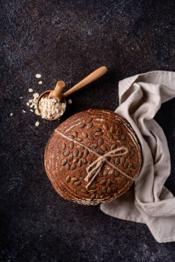 Bir ızgarada tam tahıllı un ve balkabağı tohumlarından fırınlanmış ekşi ekmek, zeytin yağı ve siyah zeytin siyah kırsal ahşap masa. Esnaf ekmeği.