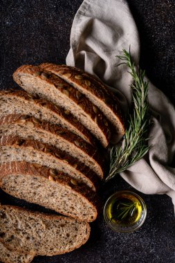 Tam tahıllı undan dilimlenmiş ekşi ekmek ve ızgarada kabak çekirdeği, kırsal bir ahşap masada zeytin yağı ve siyah zeytin. Esnaf ekmeği.