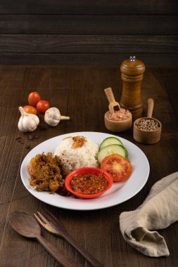 Ayam Goreng Lengkuas Kremes veya Çıtır Galangal Kızarmış Tavuk ile buğulanmış pirinç ve biber ezmesi veya beyaz tabak ve ahşap masa üzerinde sambal