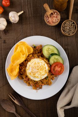 Asya Yumurtası ve Sebzeli Kızarmış Pirinç veya Nasi Goreng kızarmış güneşli tarafı ahşap masada beyaz bir tabakta.