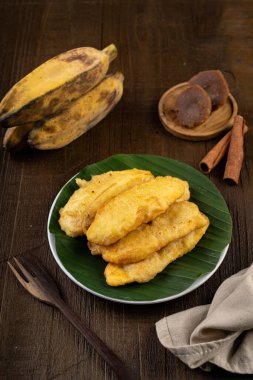 Kızarmış tatlı gevrek muz, beyaz tabak ve muz yaprağı