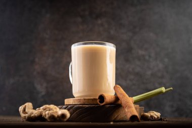 Sıcak zencefil veya Wedang susu jahe sütlü esmer şeker, tarçın, limon otu ve ahşap masa üzerinde baharat karanfili.