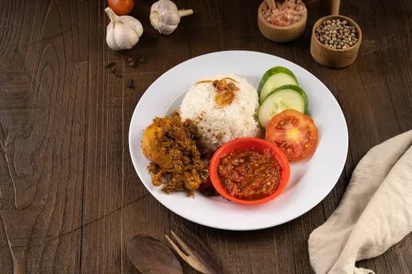 Ayam Goreng Lengkuas Kremes veya Çıtır Galangal Kızarmış Tavuk ile buğulanmış pirinç ve biber ezmesi veya beyaz tabak ve ahşap masa üzerinde sambal