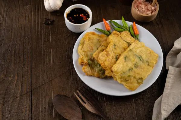 stock image Deep fried tempeh or Tempe mendoan goreng made from soy bean with flour batter and spring onion on white plate. street food