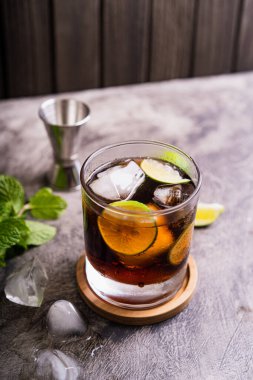 Soğuk Küba Libre ya da Long Island buzlu çay kokteyli. Kahverengi rom, kola, nane, limon, muddler, jigger ve cam karışımı.