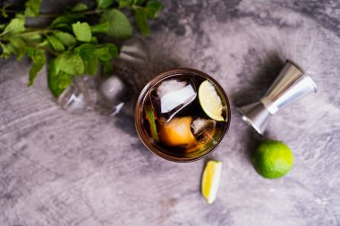 Soğuk Küba Libre ya da Long Island buzlu çay kokteyli. Kahverengi rom, kola, nane, limon, muddler, jigger ve cam karışımı.