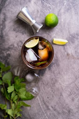 Soğuk Küba Libre ya da Long Island buzlu çay kokteyli. Kahverengi rom, kola, nane, limon, muddler, jigger ve cam karışımı.