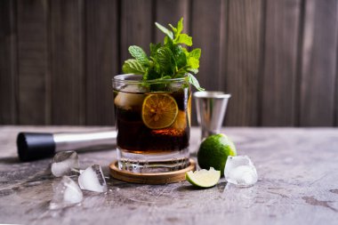 Soğuk Küba Libre ya da Long Island buzlu çay kokteyli. Kahverengi rom, kola, nane, limon, muddler, jigger ve cam karışımı.