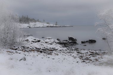 First snow by the sea in December. The picture was taken in connection with a walk in the northern part of Holmon, Sweden. Completely windless and no waves. clipart