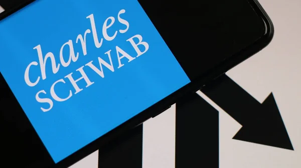 stock image Charles Schwab logo with a downward arrow chart in the background.