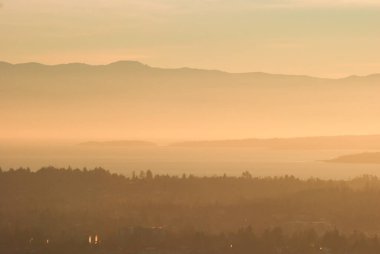 Vancouver Adası 'nın güneyinde, Olimpiyat Yarımadası' na yakın, puslu ve dumanlı bir gün batımı var..