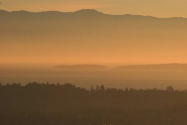 Vancouver Adası 'nın güneyinde, Olimpiyat Yarımadası' na yakın, puslu ve dumanlı bir gün batımı var..