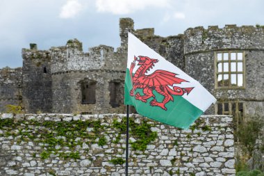 Tarihi bir şatonun önünde ejderha sembollü bir Galler bayrağı dalgalanmaktadır.