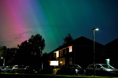 Kuzey ışıkları veya Aurora Borealis uzayda bir güneş fırtınası sırasında meskun bir caddenin üzerinde gece gökyüzünde renkli ışıklar sağlar.