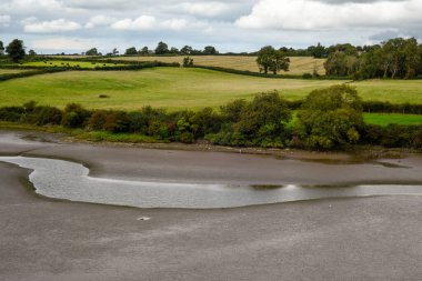 Estuary landscape at low tide when the river bed is visible clipart