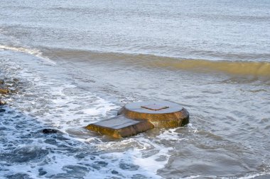 Concrete sewer pipes in the ocean leading to marine outfall into the sea potentially polluting the environment clipart