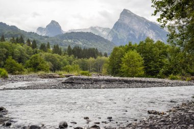 Bir ormanın üstündeki dağ sırası güzel dramatik bir manzaranın içindeki bir nehir.