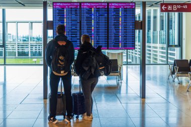 Kalkış bilgilerini gösteren genç bir çift uçuşlarını bekliyorlar..