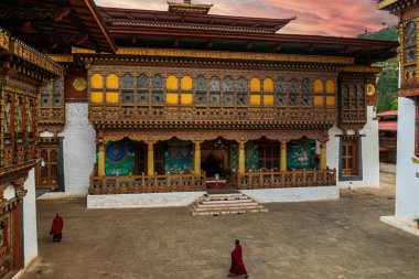 Geleneksel kırmızı elbiseli iki Budist keşiş Punakha Dzong manastırında yürüyor.