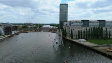 Spree Nehri 'nde Molekül Adam heykeli ve sakin suyu çevreleyen çeşitli binalar. Açık gökyüzü güneşli bir gün. Berlin, Almanya