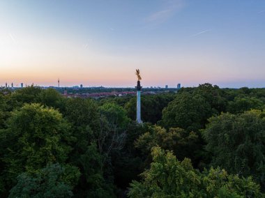 Friedensengel overlooking a beautiful sunset sky over the surrounding park in Munich clipart