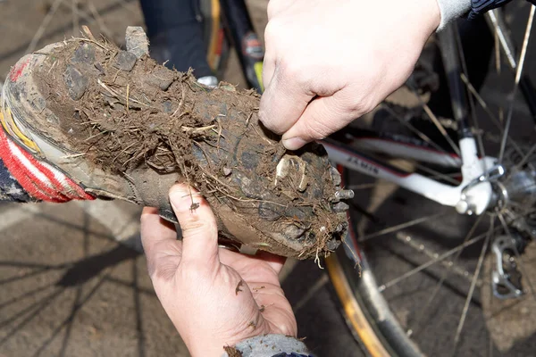 Man cleaning dirty bicycle shoe after cross-country off-road cycling