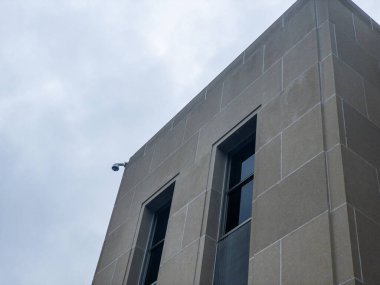 Kuzey Dakota Eyalet Meclisi 'nin gri binasının köşesindeki CCTV kamerası. Bulutlu gökyüzüne karşı alçak açılı çekim